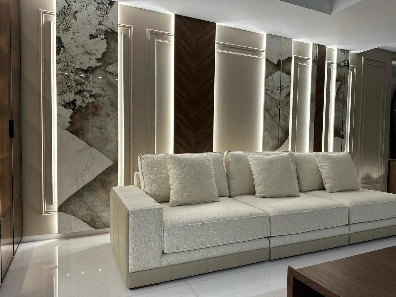 Salon avec canapé blanc, panneaux de marbre et boiserie à chevrons